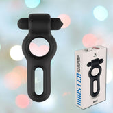 A sleek silicone Velv'Or Drake Dual-Ring Vibrating Cock Ring in black is showcased beside its packaging box against a softly blurred background. The box displays an image of the product and features text in light blue and black.